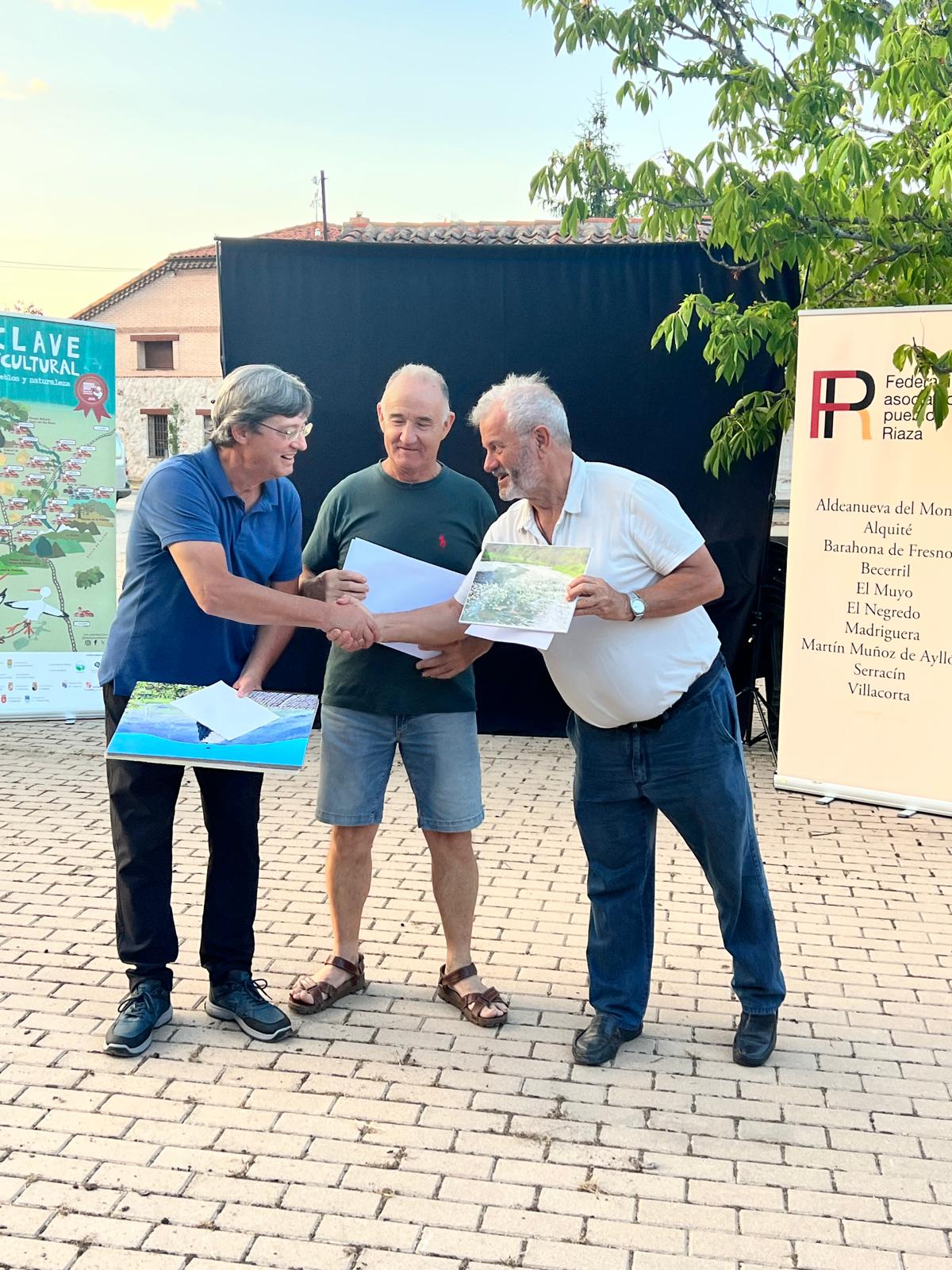 Pedro Morales recoge el primer premio en representación del autor de manos  de Juan Cardona, presidente de la Federación y de Ernesto Bernal, presidente de la asociación de Barahona de Fresno.